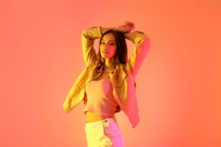 Pretty young woman in stylish clothes on color background